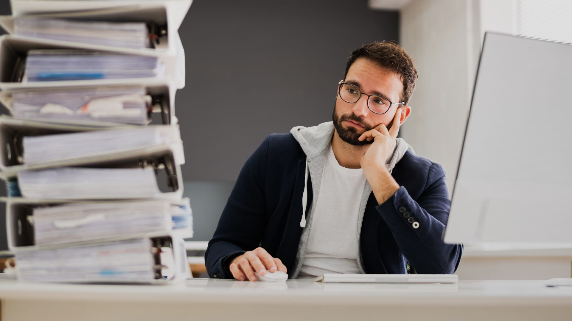Professional man staring at files on his office desk in a withdrawn mood