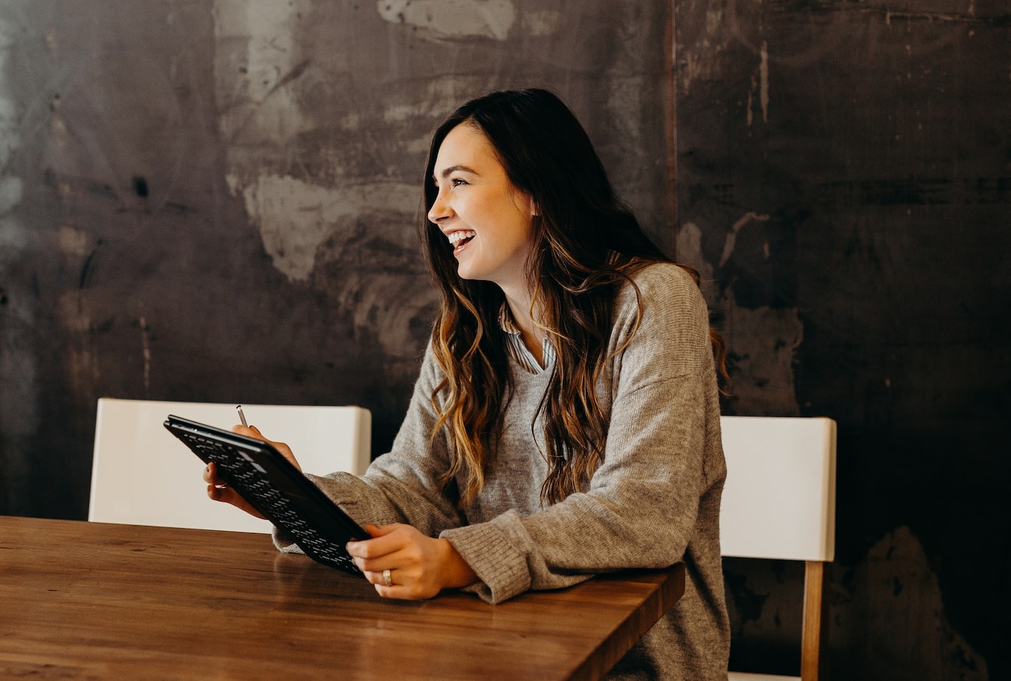 woman sitting around table holding tablet