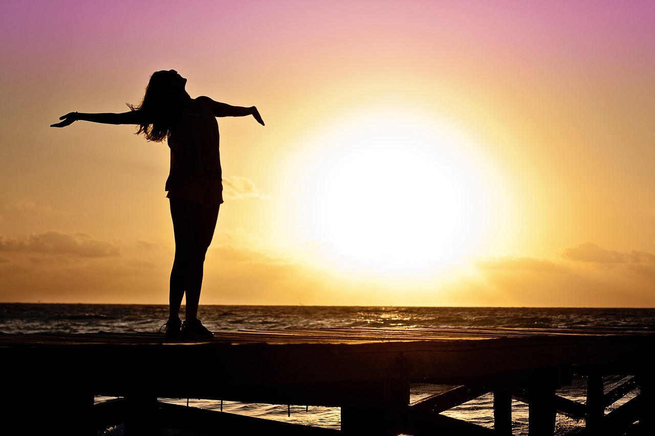 woman looking at sunset with open arms